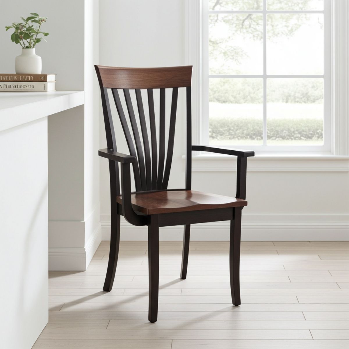 A wooden dining chair with a dark brown seat and backrest, black armrests, and a spindle back, positioned in a bright, modern room next to a window.