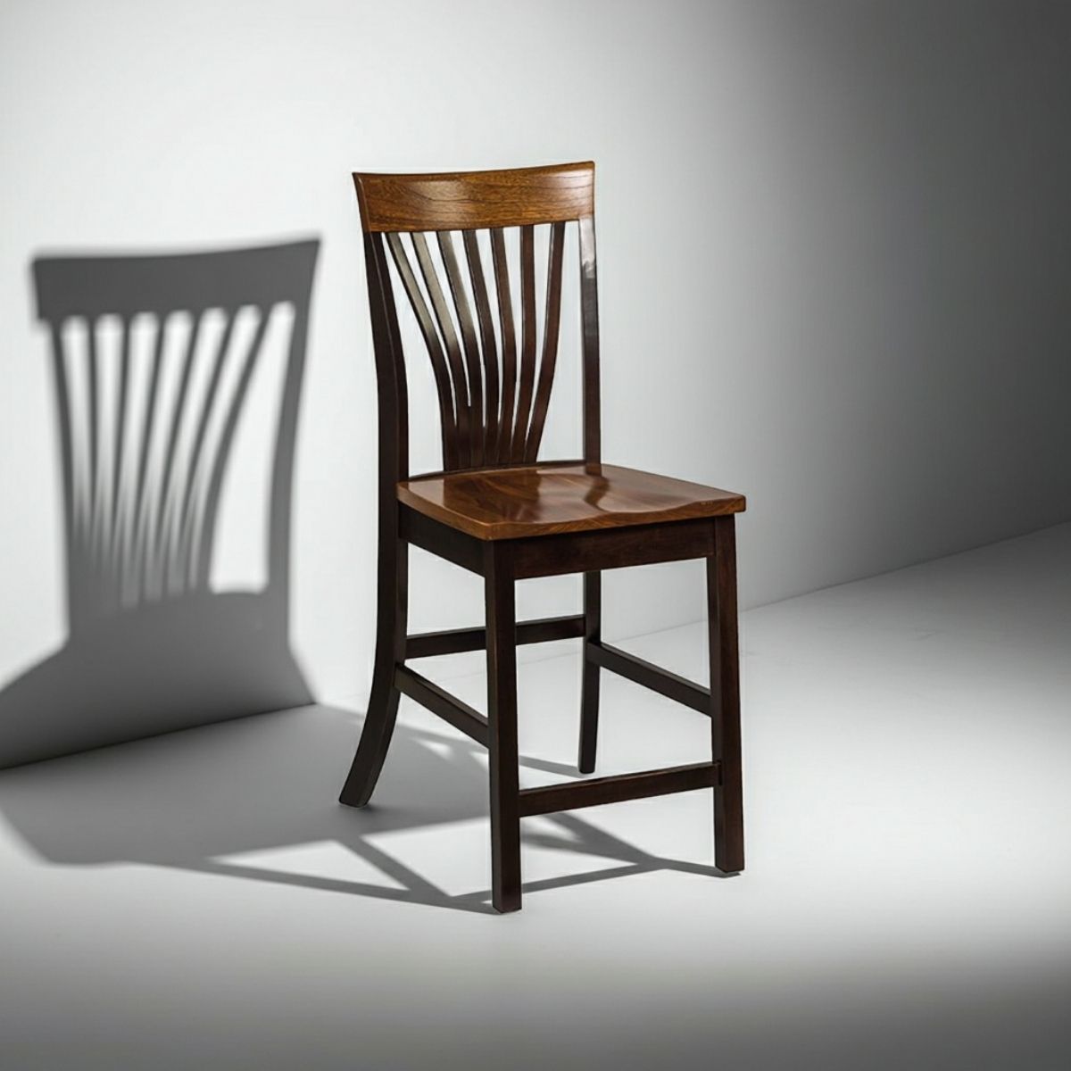 A wooden dining chair with a slatted back and a square seat, shown in a studio setting with dramatic side lighting and a cast shadow on a light gray background.