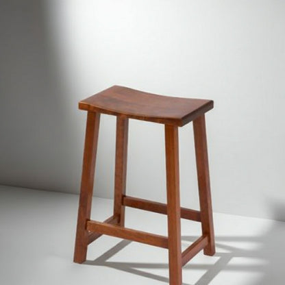 A wooden bar stool with a curved seat and four legs, shown on a light gray studio background with a cast shadow.