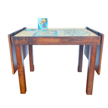 A wooden jigsaw puzzletable with a colorful jigsaw puzzle on the recessed tabletop and a jigsaw puzzle box standing upright, shown on a plain white background.