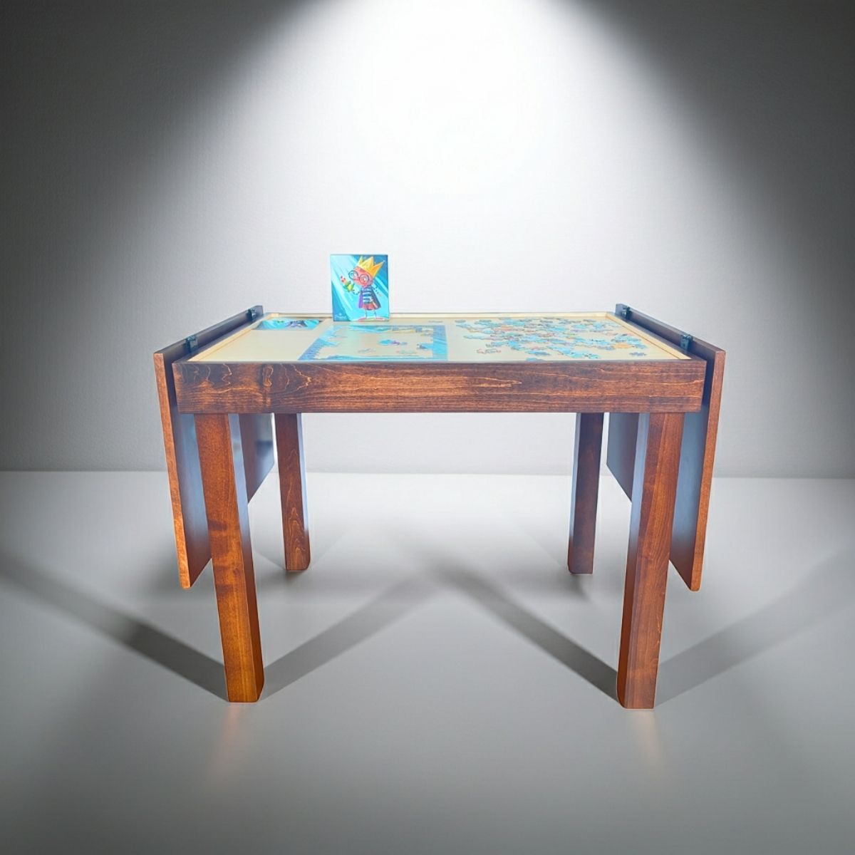 Wooden jigsaw puzzle table with a jigsaw puzzle on the recessed playing area on a gray background